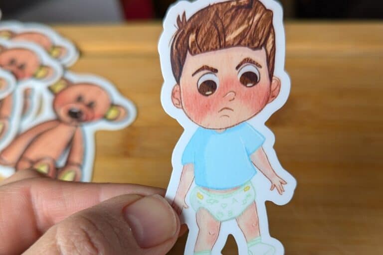 hand holding a toddler sticker, toddler in blue shirt, diaper, and socks