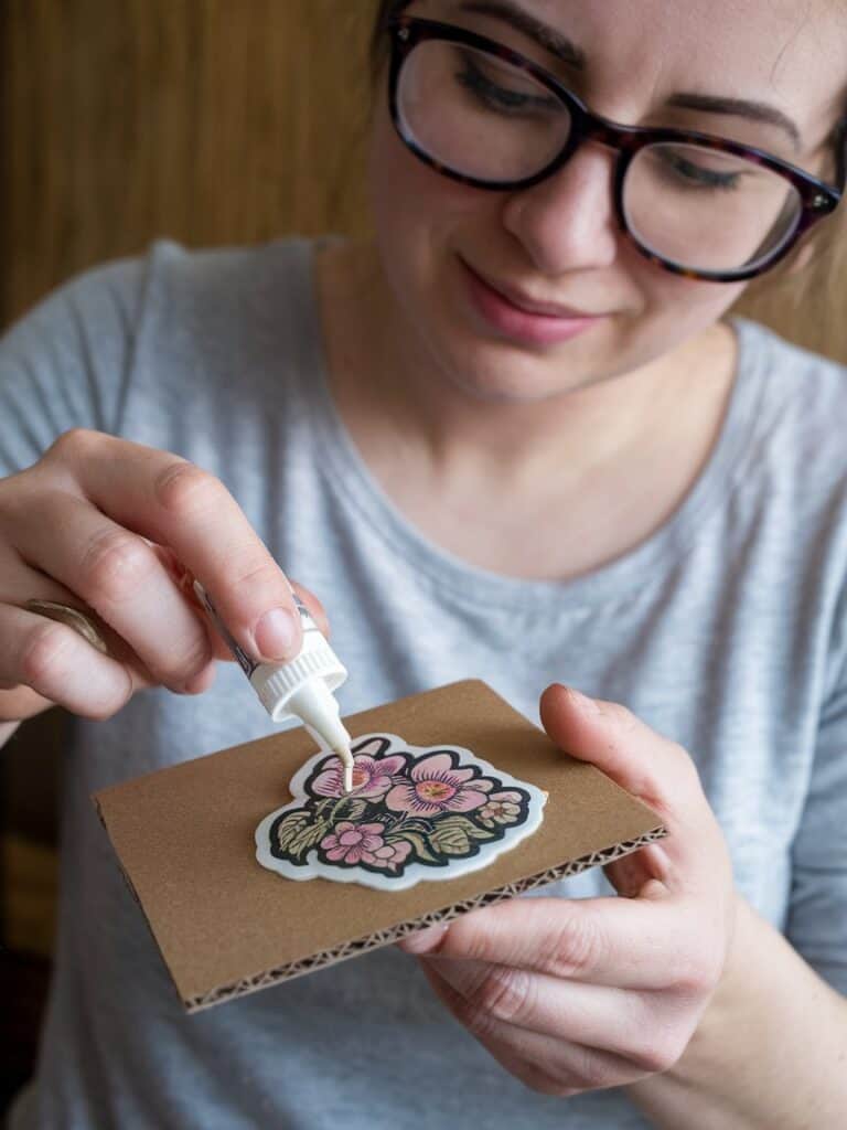 a woman applying 3d glue to asticker to make a domed pin