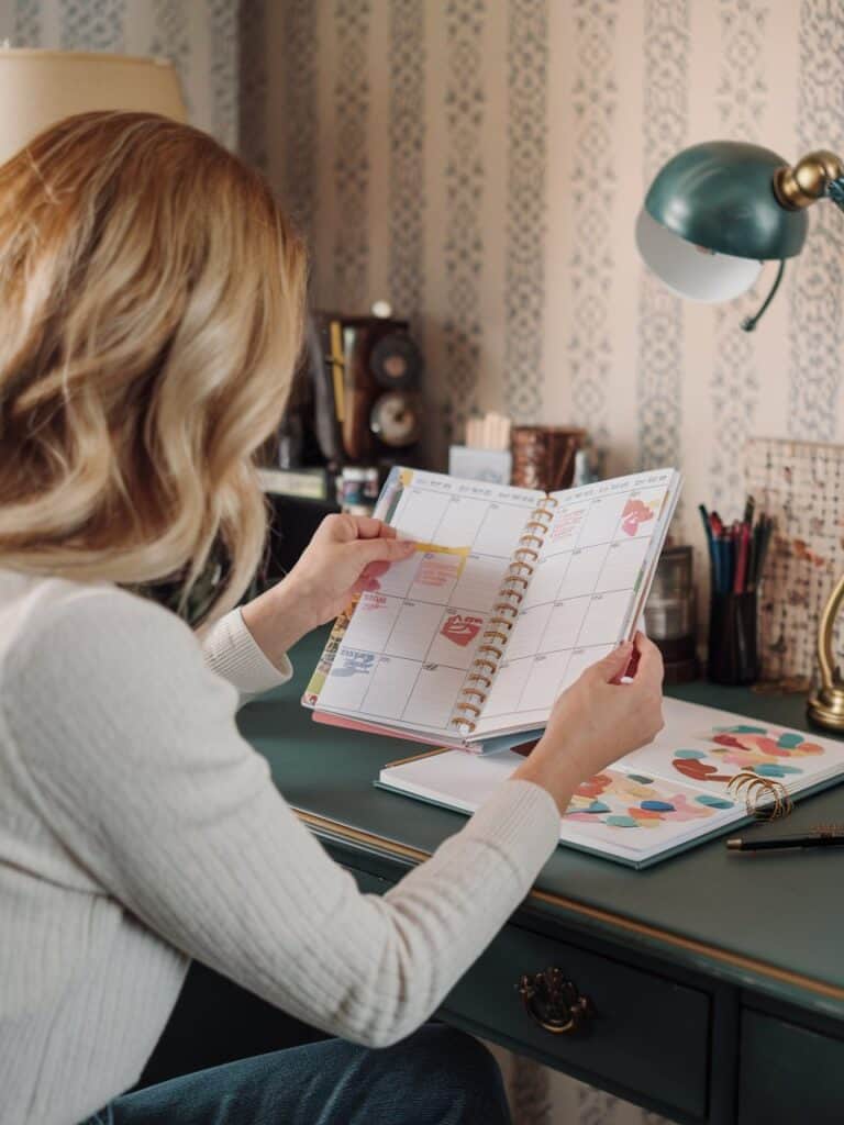 a woman sitting looking at her sticker journal layout