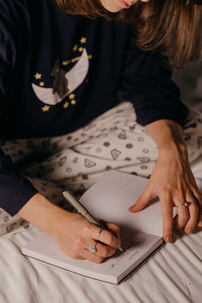 A woman in cozy pajamas writing in a notebook, indoors