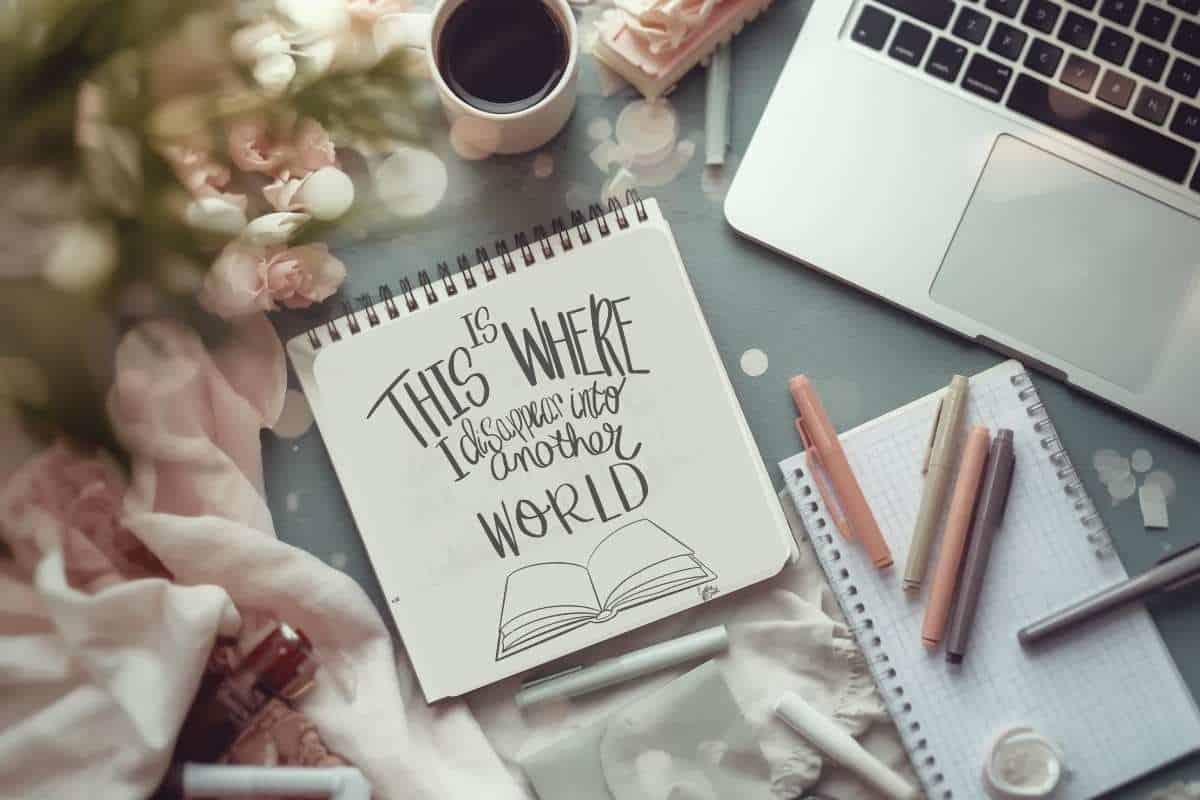 A cozy flatlay of sketchbook, notes, laptop and art supplies representing capturing creative ideas out of chaos.