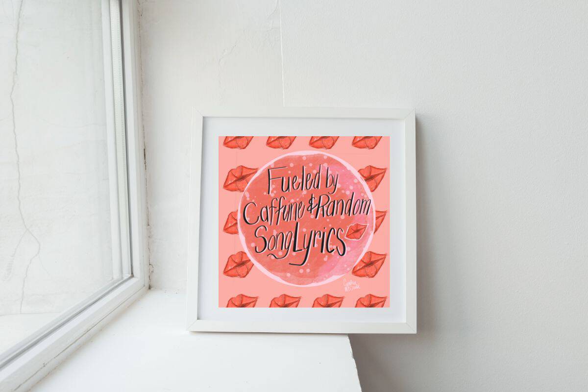 A framed 12x12 wall art print with a pink background and red lips pattern sits on a white windowsill; the artwork reads "Fueled by Caffeine & Random Song Lyrics."