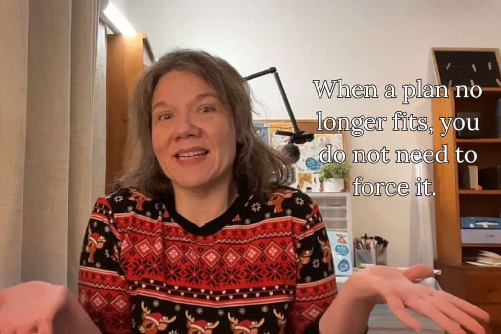 A woman shrugs with a warm smile, sitting in a creative home office; text reads “When a plan no longer fits, you do not need to force it.”